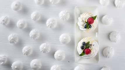 Dessert Pavlova with raspberries, blueberries and mint on a white table.