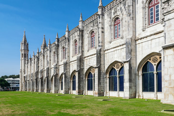 View perspective on the walls of the monastery Jeronimos, against the blue sky, with a green lawn