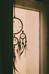 Silhouette of a small Dreamcatcher hanging in a window in the evening light