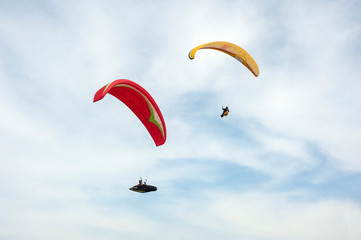 Paragliding over the green field in summer sunny day. Two paragliders fly over green field near Dnister river in Ukraine.