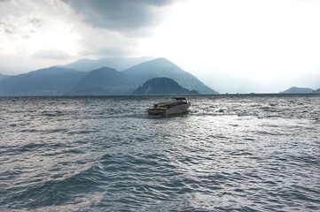 The boat is floating on the storming Lake Como before a thunderstorm.