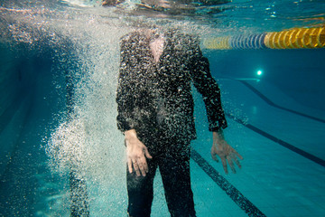 man wearing business suit underwater