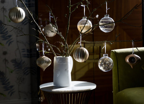 Gold toned Christmas baubles displayed on a sunny table. Alternative Christmas tree.