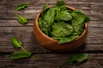 Spinach in a wooden plate on a wooden background