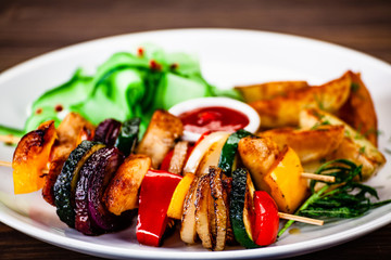 Kebabs - grilled meat with french fries and vegetables wooden background