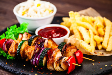 Kebabs - grilled meat with french fries and vegetables wooden background
