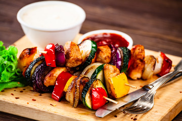 Kebabs - grilled meat with french fries and vegetables wooden background