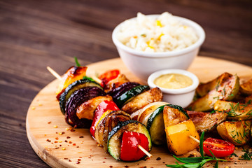 Kebabs - grilled meat with french fries and vegetables wooden background