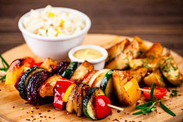 Kebabs - grilled meat with french fries and vegetables wooden background
