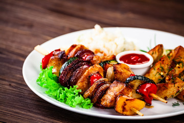 Kebabs - grilled meat with french fries and vegetables wooden background