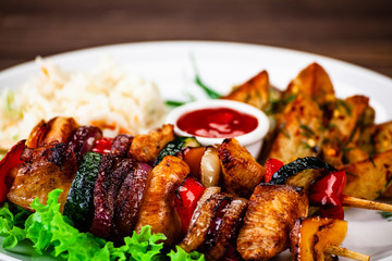 Kebabs - grilled meat with french fries and vegetables wooden background