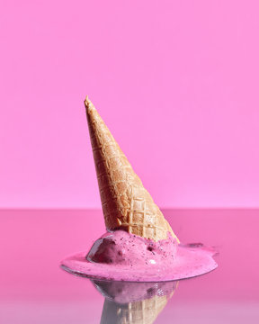 Scoops of berry melting ice cream in wafer cones are reflected o