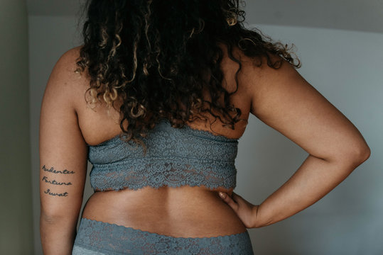 A beautiful plus size woman in her twenties lounging at home in a bra and underwear