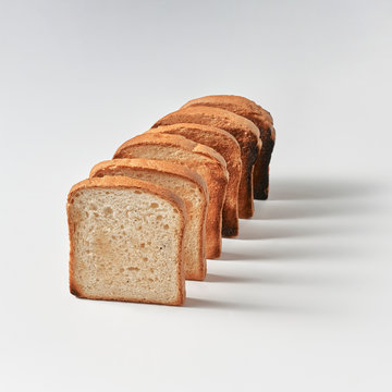 Row of toast bread pieces on gray background with copy space and shadows. Sandwich ingredient