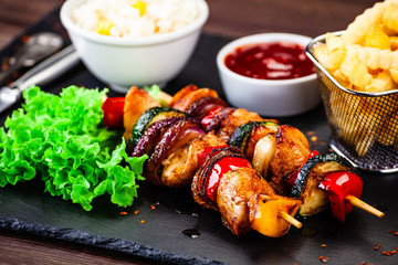 Kebabs - grilled meat with french fries and vegetables wooden background
