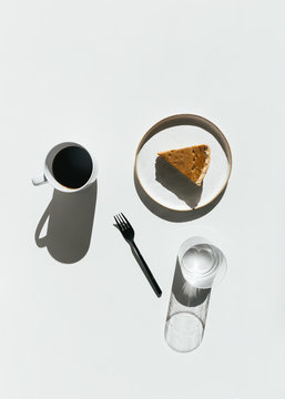Still life with coffee cup, fork, pumpkin pie, light and shadow on white background