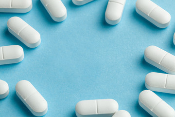 White pills on blue background. One tablet is broken in half, reducing the dose of the medicine....