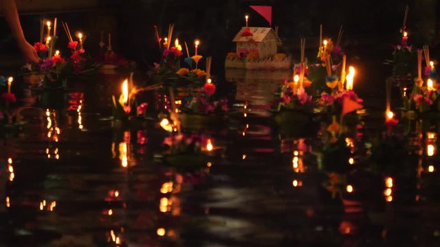 Paper lotus flower with candle floating on a river at night in Loy krathong festival, traditional Siamese new year festival celebrated in Thailand.