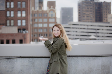 Fototapeta premium Young lady on rooftop holding glass ball in front of city backdrop