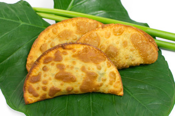 Tradional Brazilian fried pastry called pastel on Exotic edible plant  leafcalled taioba