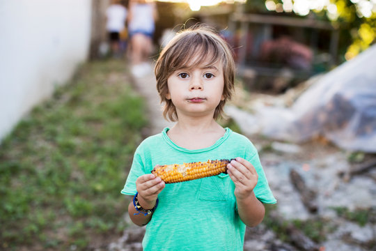 3 year old boy eating baked corn