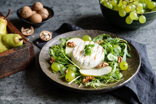 Grilled Camembert cheese with fresh arugula, green grapes, pears and walnut