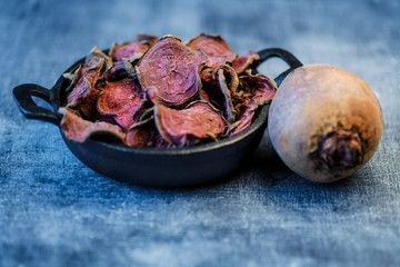 vegetarian pile of healthy beet chips Purple Baked Beet Chips Vegan snacks, vegetable chips in canvas bag and ceramic bowl, rustic still life, selective focus.