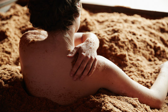 Woman soaking and exfoliating her skin in fermented Japanese cedar enzyme bath