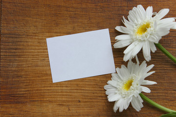 Obraz premium White paper and flowers daisy on a wooden background