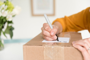 Woman writing address on package