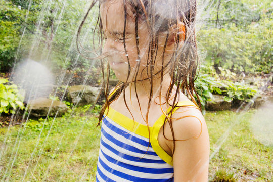 girl getting sprayed in face with sprinkler