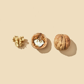 Set of whole, halved and middle of a walnut on a beige background with shadow and copy space. Healthy food. Flat lay