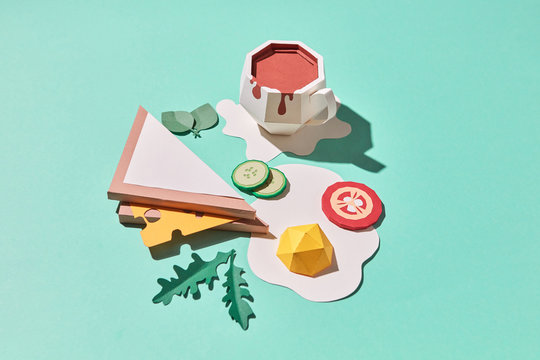 Craft paper sandwich with cheese, fried eggs, sliced tomato, cucumber, arugula and a cup of coffee on a blue background with copy space. Flat lay