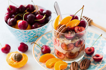 Healthy breakfast: overnight oats with fresh black cherries, peaches and pecans in a glass 