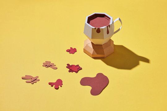 Paper craft cup of coffee with splashes and reflection of shadows on a yellow background with copy space. Flat lay