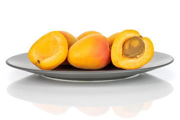 Naklejka na ściany i meble Group of four whole two halves of fresh orange apricot with an apricot stone on a gray ceramic plate isolated on white background