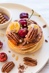 Breakfast concept. Pancakes with black cherries, bananas, pecans, yogurt and honey.