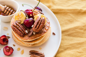 Breakfast concept. Pancakes with black cherries, bananas, pecans, yogurt and honey.