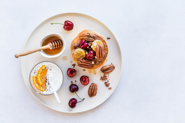 Breakfast concept. Pancakes with black cherries, bananas, pecans, yogurt and honey.
