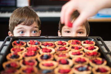 Two kids looking at preparation of cupcakes