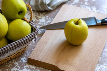 Knife and apple on a cutting board on a table in the kitchen. Chantecler apples.