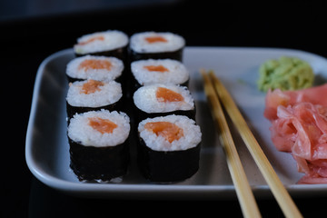 Sushi roll with seafood and soy sauce, wasabi and ginger. Sushi roll on a black background