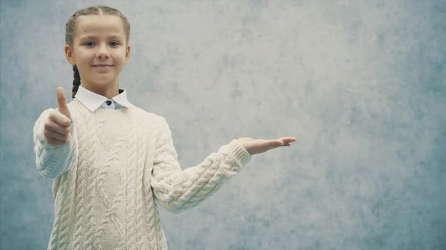 Little schoolgirl presenting an idea and pointing her thumb finger up.