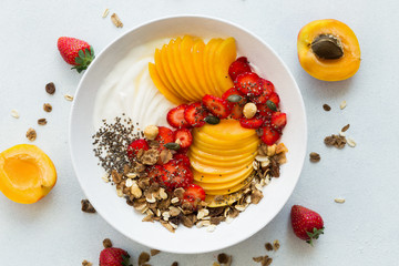 Healthy breakfast. Greek yogurt with fresh apricots, strawberries, walnuts, muesli and honey. Top view