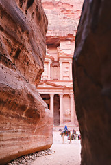 Peering through the rock walls at bedouin guides sitting with their camels in front of the Treasury at Petra.