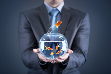 Businessman holding goldfish in fishbowl