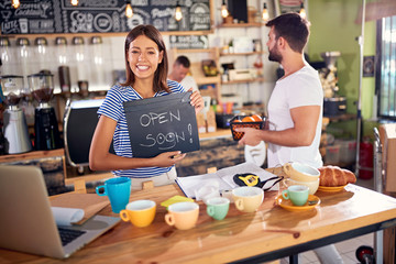 Happy woman store owner with open sign..