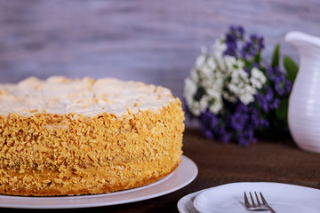Cake Napoleon of puff pastry with nuts and flowers on background