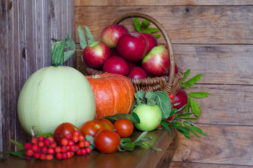 basket with apples on a wooden background. harvesting autumn and summer harvest. vegetables and fruits pumpkin, zucchini, apple, rowan, pea, cherry. soft focus. copy space.