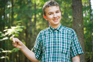 teenager boy with mushroom in the forest in summer day
